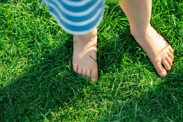 Босонога дитина стоїть під час ходьби на зеленій траві, опудало — стокове фото
