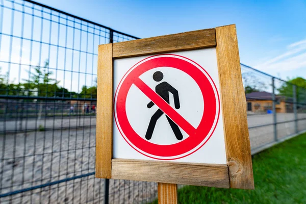 Divieto Nessun segno pedonale accanto alla recinzione. Segni proibiti figura dell'uomo che cammina in un cerchio incrociato isolato su sfondo bianco . — Foto Stock