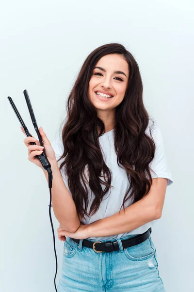 Portrait of pretty cute girl using a straightener for her curly hair, isolated on white background — Stok fotoğraf