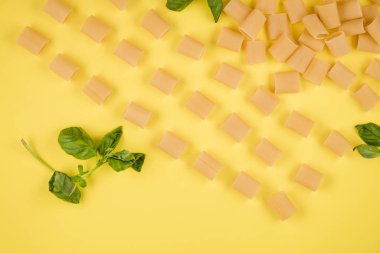The yellow background shows Italian paste, basil. concept of italian cuisine.