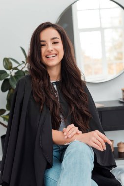 Happy beauty client sitting on chair and smailing at camera and waiting