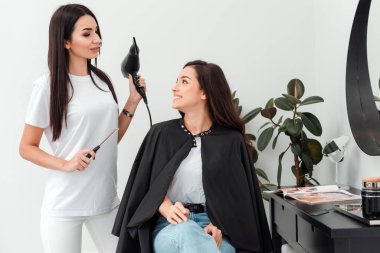 Professional hairdresser with drying in his hand advises his client what hairstyle is best to do