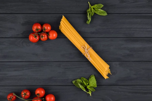 Sobre un fondo oscuro son ingredientes italianos: pasta, tomates, albahaca — Foto de Stock