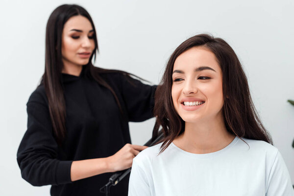 A professional, focused stylist works with a smiling brunette hair