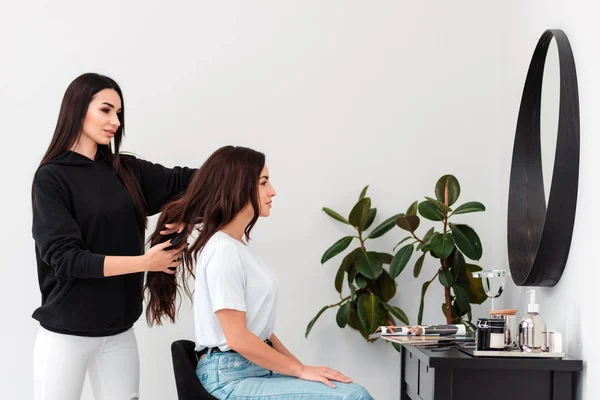 Una bella ragazza pettina con cura i capelli del suo cliente — Foto Stock