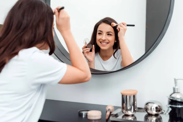 Bella, sorridente, giovane donna che si trucca — Foto Stock