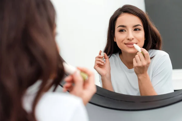 Attraente, carina bruna disegna le labbra con il rossetto, guardandosi allo specchio — Foto Stock