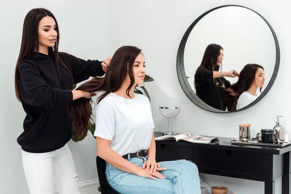 Il parrucchiere sorridente e professionale pettina bei capelli al cliente — Foto Stock