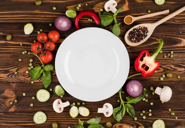 En una mesa de madera se encuentra un plato, rodeado de productos italianos y especias — Foto de Stock