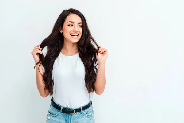 Jonge vrouw poseren en glimlachen, rechttrekken haar haar over witte achtergrond — Stockfoto
