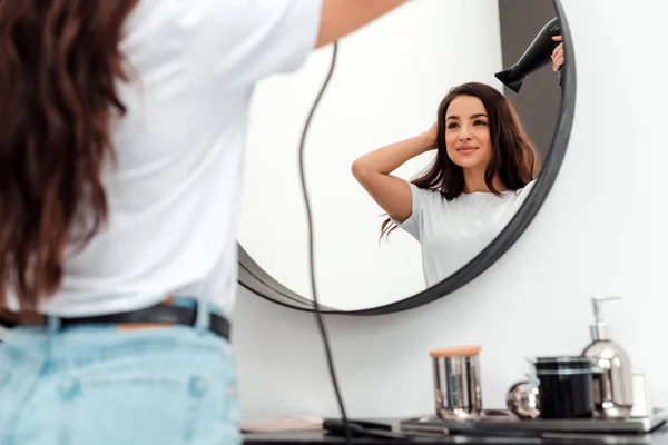 Bella giovane donna asciuga i suoi bei capelli e si guarda allo specchio — Foto Stock