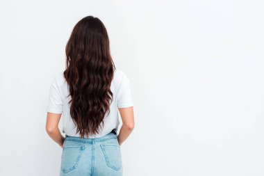 Beautiful young woman with long dark hair wearing a t-shirt posing on white background