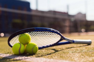 Güneş ışığı altında sert kortta üç tenis topu ve raket makro görüntü