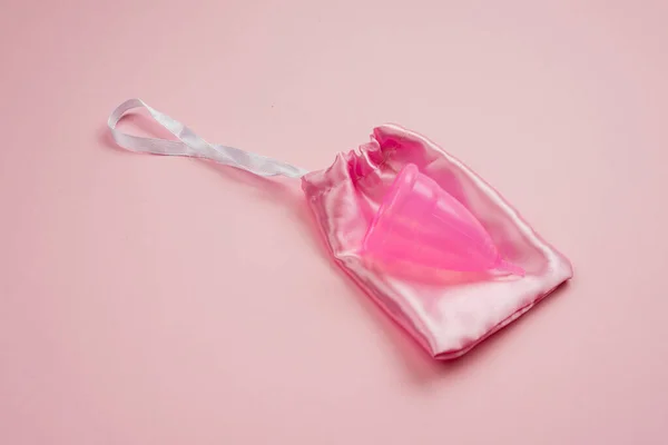 Menstrual  silicone cup lying on silk bag on pink background — Stock Photo, Image