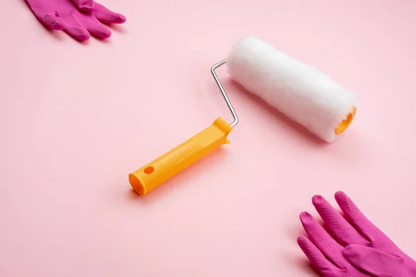 Paint roller  and latex gloves lying on diagonal on pink backgro — Stock Photo, Image