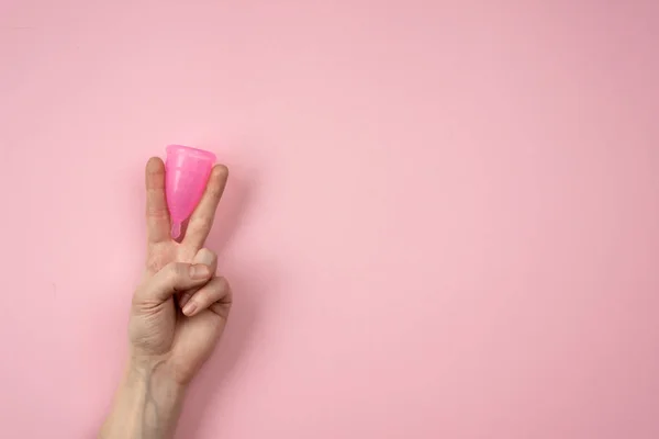 Roze menstruatiecup in de vrouwelijke arm geïsoleerd op een roze backgro — Stockfoto