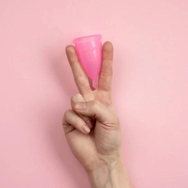 Close-up van de hand van de vrouw met menstruatie cup op roze achtergrond. Vrouwen gezondheid concept, nul afval alternatieven — Stockfoto