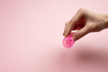 Female hands show how to use a menstrual cup.
