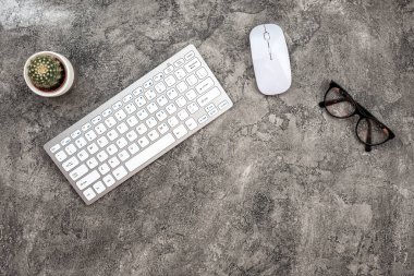 Top view plaster background with keyboard, glasses, mouse and a 