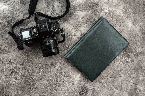 Fotoaparát a zápisník ležící na pozadí omítky — Stock fotografie