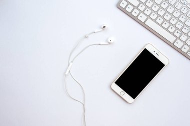 White office  desk with a smartphone, earphones   - Top view