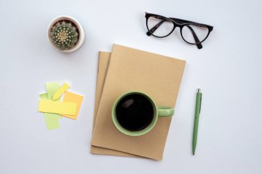 Office   desk with a glasses, cup of coffee standing on a notebo