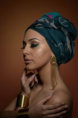 Sarık güzel kadın. Genç güzel kadın Türban ve altın aksesuarlar ile. Güzellik modaya uygun kadın Türban içinde sarılı tüyleri ile. Çok beyaz modeli Studio poz küpeler.
