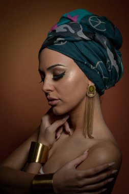 Sarık güzel kadın. Genç güzel kadın Türban ve altın aksesuarlar ile. Güzellik modaya uygun kadın Türban içinde sarılı tüyleri ile. Çok beyaz modeli Studio poz küpeler.