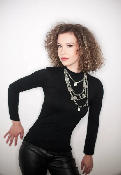 Happy young woman with black blouse against white wall. Young woman with long curly hair posing in studio against white wall — Stock Photo, Image