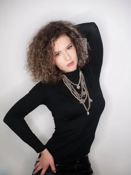 Happy young woman with black blouse against white wall. Young woman with long curly hair posing in studio against white wall — Stock Photo, Image