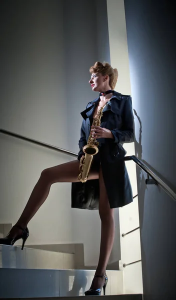 Sexy attractive women with saxophone and long legs posing on stairs. young sexy woman play sax.musical instrument.jazz.Portrait of a sexual young woman posing with saxophone — Stock Photo, Image