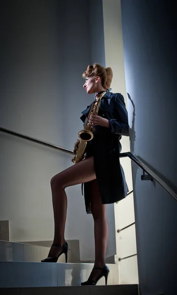 Sexy attractive women with saxophone and long legs posing on stairs. young sexy woman play sax.musical instrument.jazz.Portrait of a sexual young woman posing with saxophone — Stock Photo, Image