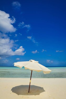 pastoral tropikal kum plaj şemsiyesi. Beyaz plaj şemsiye ve mavi gökyüzü. Güneş ve plaj şemsiyesi. Yaz plaj manzara .