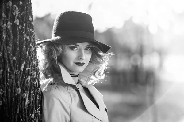 Belle femme blonde avec manteau crème, longues jambes et chapeau noir dans une scène d'automne.Portrait d'une très belle jeune femme élégante et sensuelle aux cheveux bouclés posant dans le parc d'automne . — Photo