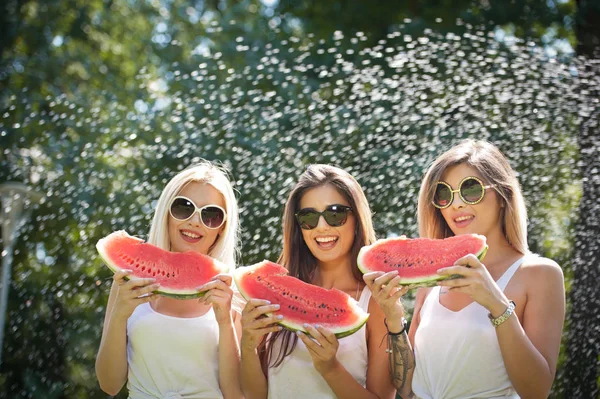 Beautiful girls with sunglasses eating fresh watermelon and smiles.Happy young woman eating watermelon in park. Youth lifestyle. Happiness, joy, summer concept. — Stock Photo, Image