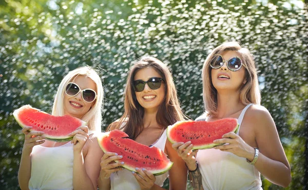 Piękne dziewczyny z okulary jedzenia świeżego arbuza i uśmiecha się. Szczęśliwa młoda kobieta jedzenie arbuza w parku. Styl życia młodzieży. Szczęście, radość, koncepcja lato. — Zdjęcie stockowe