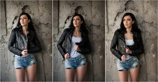 Retrato de bela mulher jovem sexy com jeans, undershirt branca jaqueta de couro preto, em fundo urbano. Morena atraente com pernas longas perfeitas em salto alto sandálias de prata posando moda . — Fotografia de Stock