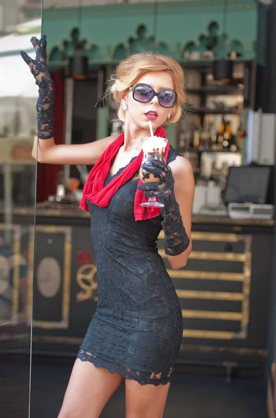 时髦的女士与短的黑色蕾丝礼服和红色围巾和高跟鞋 户外拍摄 年轻迷人的短发金发碧眼的女人与太阳眼镜摆在外面冰咖啡饮料 — 图库照片