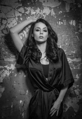 Güzel kız makyaj soyulması yeşil boya ile eski duvara poz ile. Güzel esmer siyah. Atış çekici siyah saçlı kadın, kentsel. Uzun saçları ve harika gözleri model siyah elbise ile 