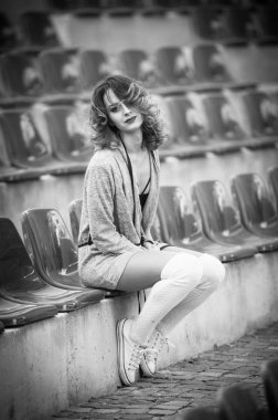 bir alanın mahkemelerde uzun bacaklar ile şehvetli kız. Uzun bacaklar çekici sarışın kıvırcık saçlı tribünlerde sandalyeye rahatlatıcı. Şık genç kadın ile beyaz yün külotlu şehvetli poz