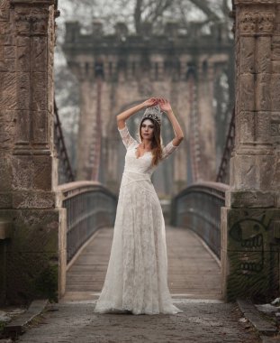 Göksel ışık ve yüzüne düşen kar taneleri demeti tadını zarif beyaz elbise giyen güzel genç bayan. Güzel esmer kız kış manzarası Bridge'de poz uzun gelinlik