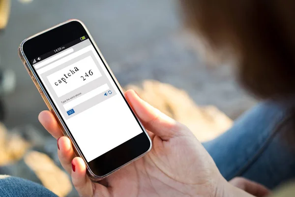 Mujer joven comprobando captcha en su teléfono móvil — Foto de Stock