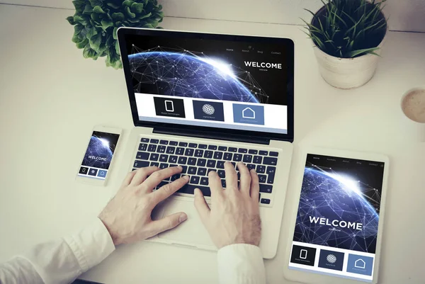 Hands writing on a laptop with phone — Stock Photo, Image