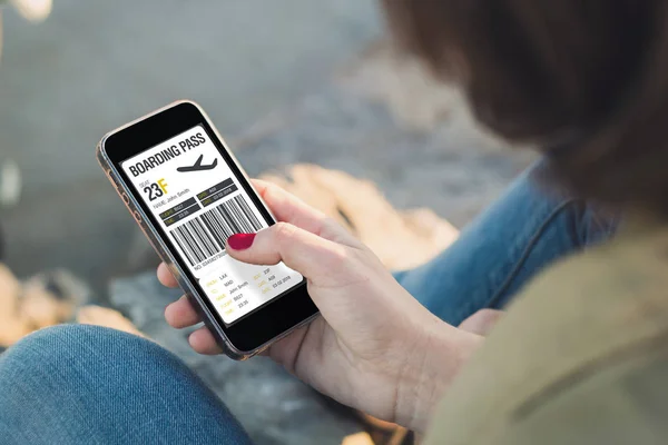 Woman touch the screen of her smartphone with boarding pass — Stock Photo, Image