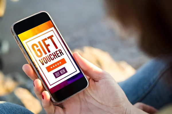 mobile marketing concept: woman using smartphone with gift voucher on screen