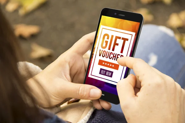 mobile marketing concept: woman using smartphone with gift voucher on screen