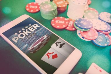 poker Web sitesinde ekran, cips ve yeşil poker masasında kartları ile Smartphone