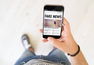 Smartphone sahte haber sitesi ile ekranda tutan adam