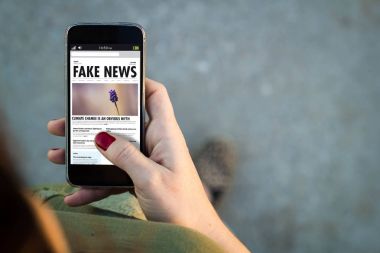 woman holding smartphone with fake news website on screen