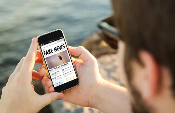 Mann Hält Smartphone Mit Fake News Website Auf Dem Bildschirm — Stockfoto